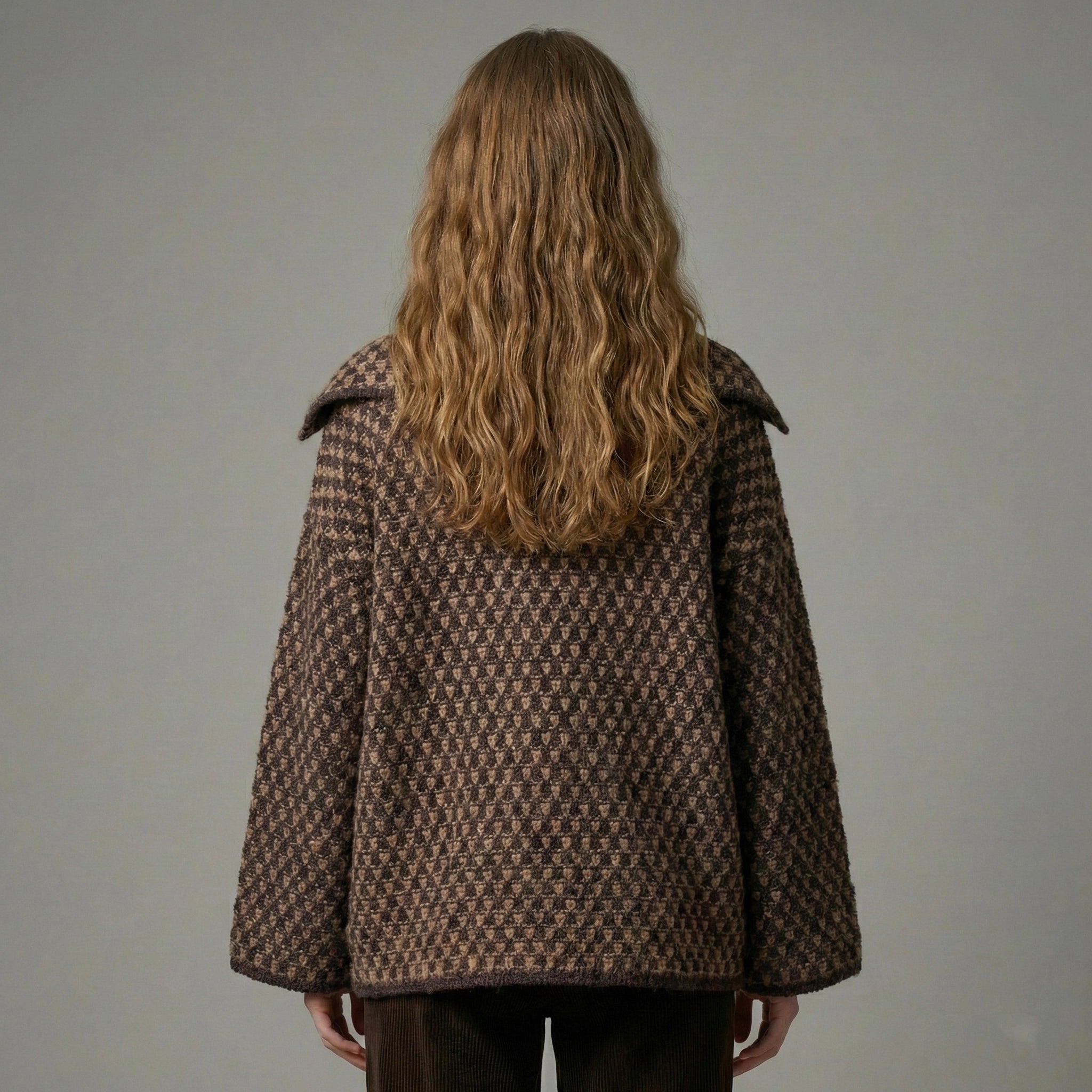 Person wearing a brown checkered coat against a plain background