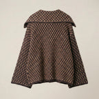 Houndstooth patterned cape on a beige background