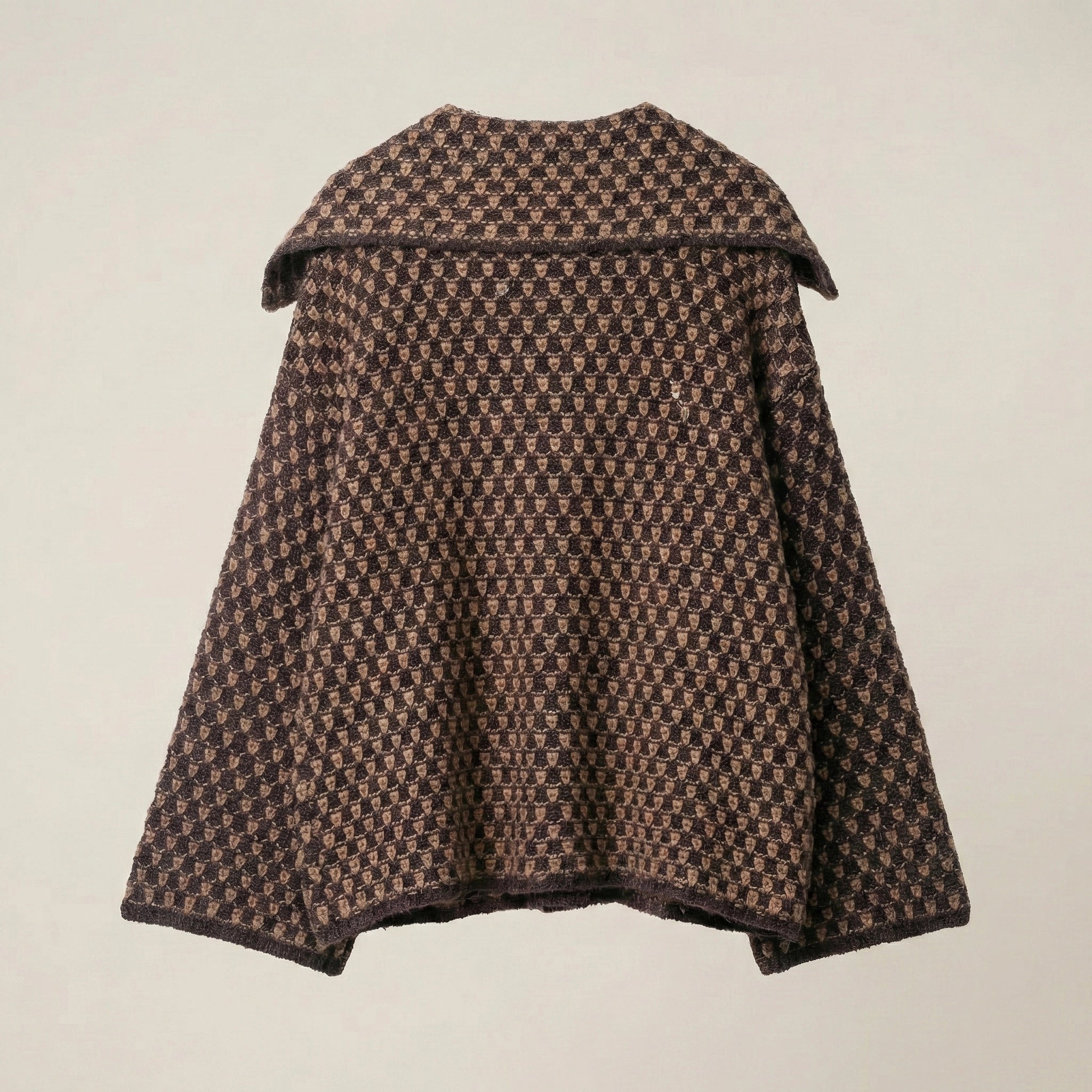 Houndstooth patterned cape on a beige background