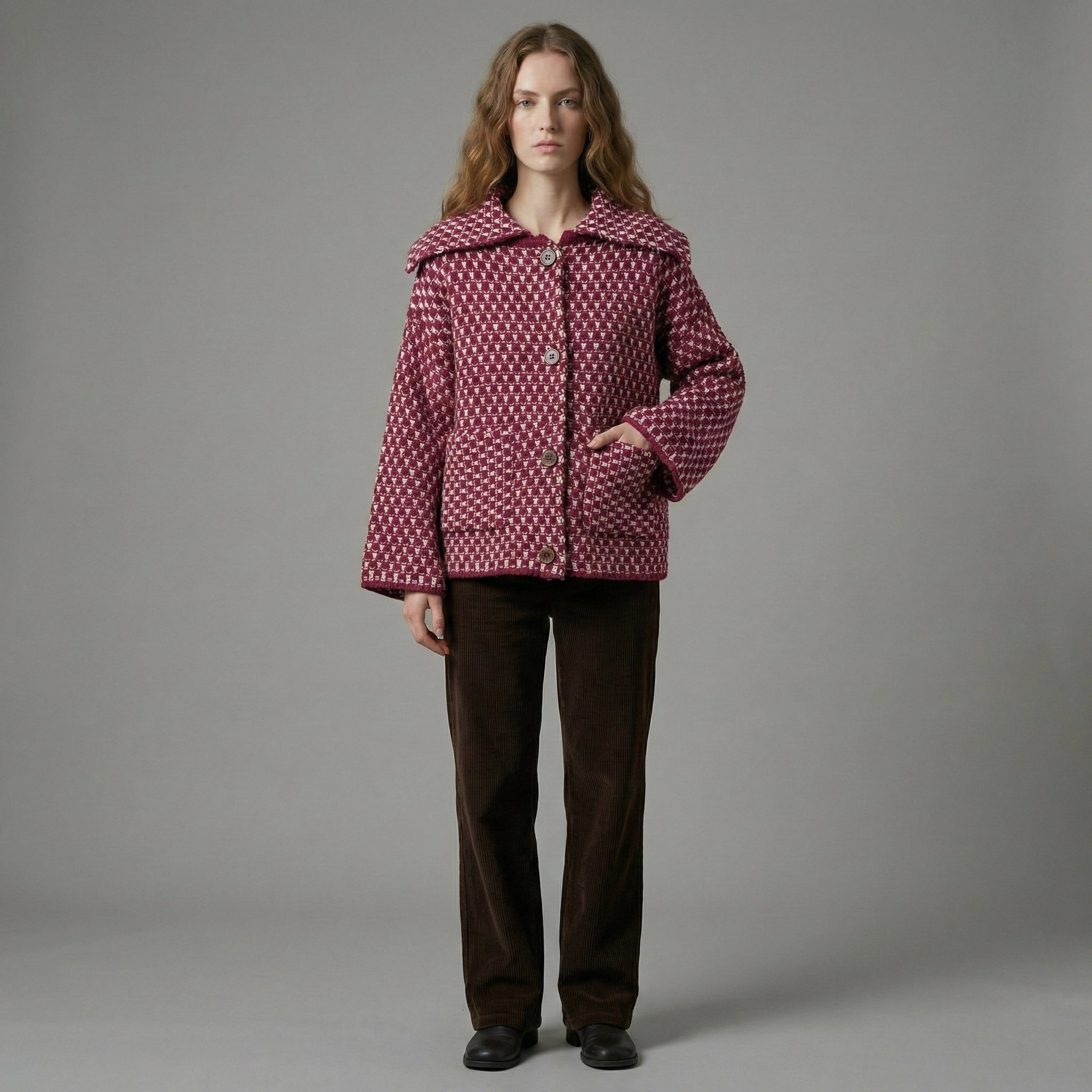 Person wearing a patterned jacket and brown pants on a gray background