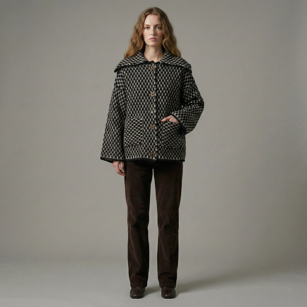 Woman wearing a patterned coat and brown pants against a plain background