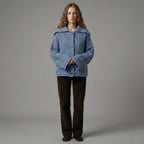 Person wearing a blue patterned coat against a gray background