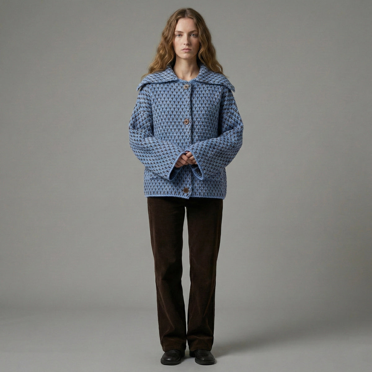 Person wearing a blue patterned coat against a gray background