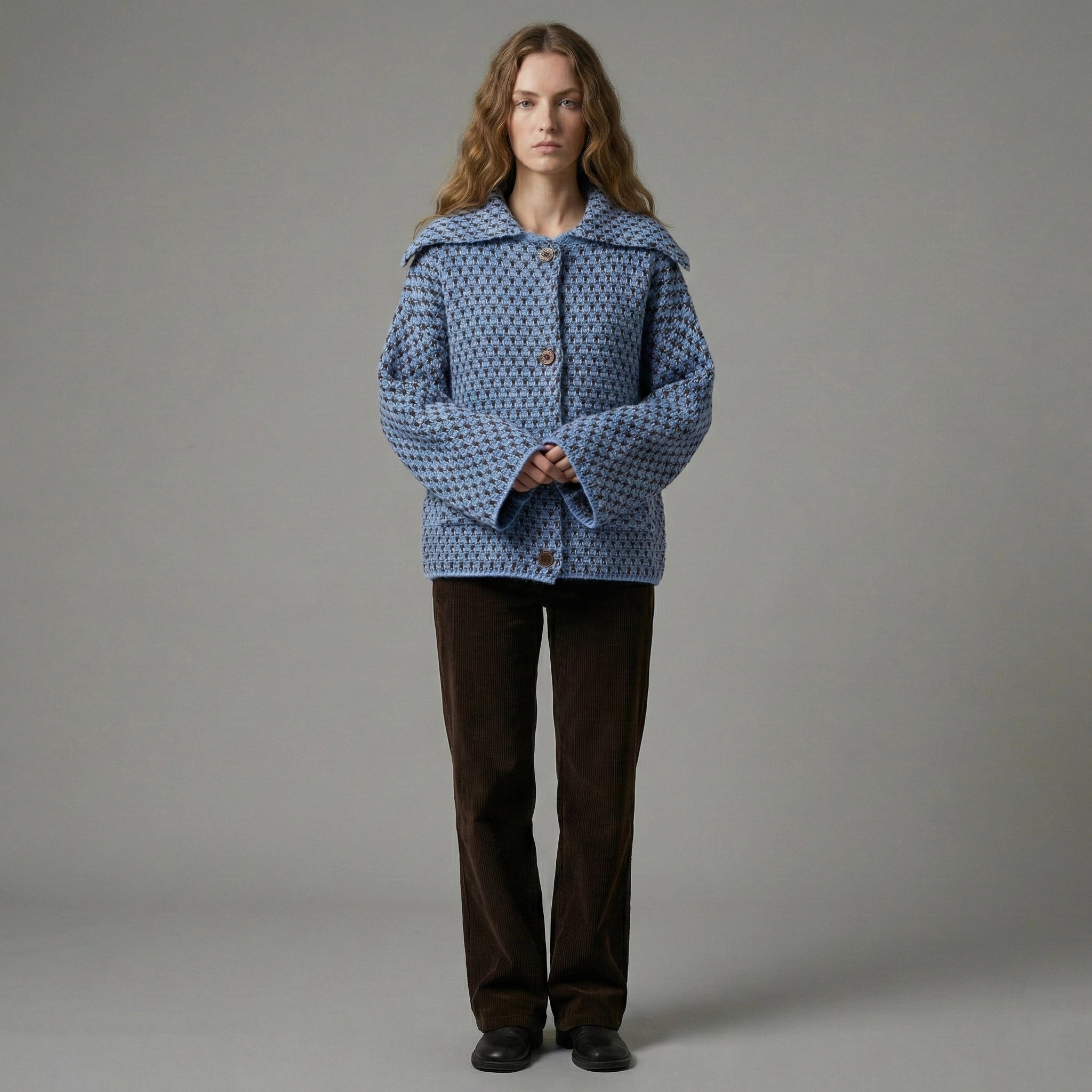 Person wearing a blue patterned coat against a gray background