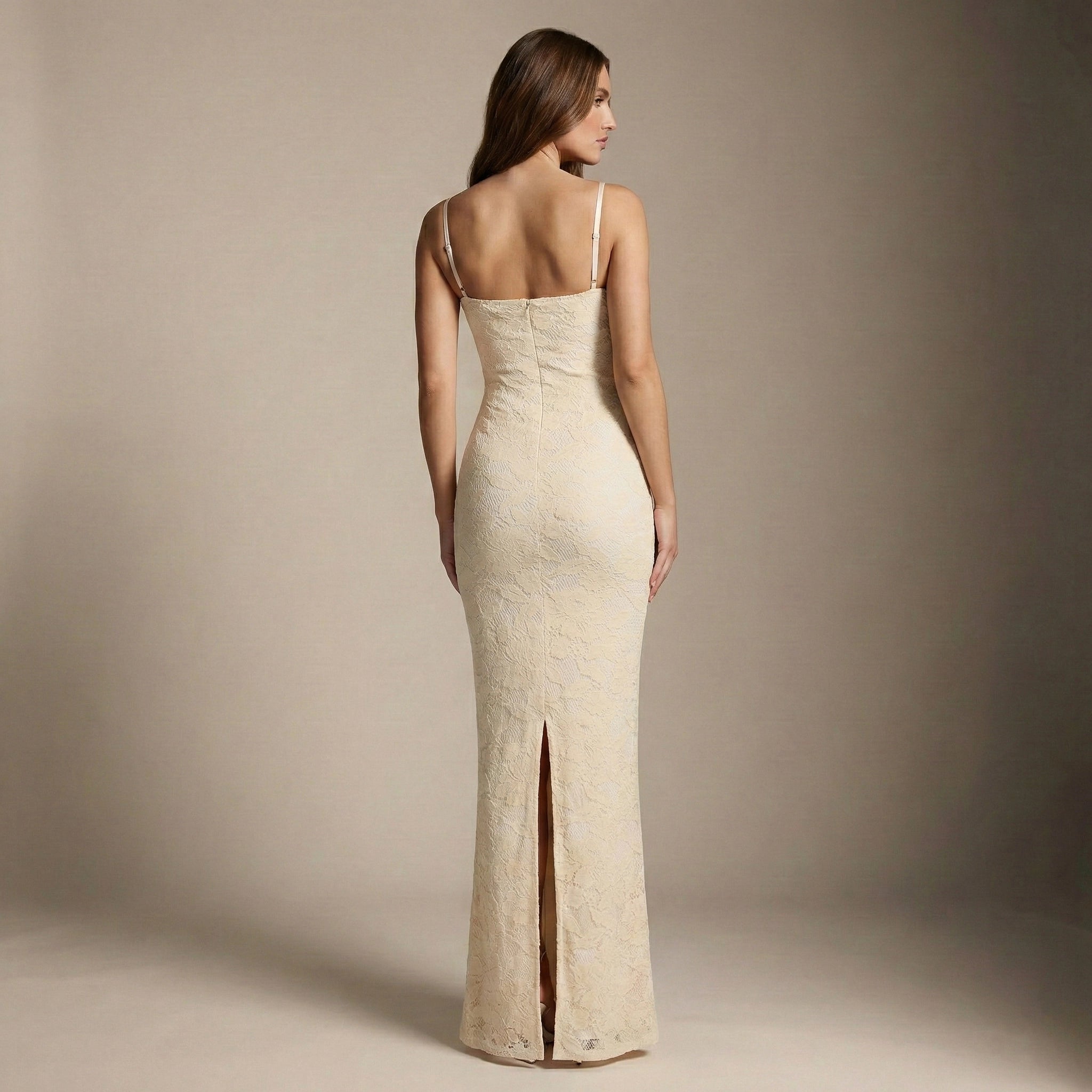 Woman wearing a beige evening gown with a slit on a plain background