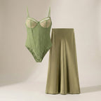 Green bodysuit and satin skirt on a neutral background