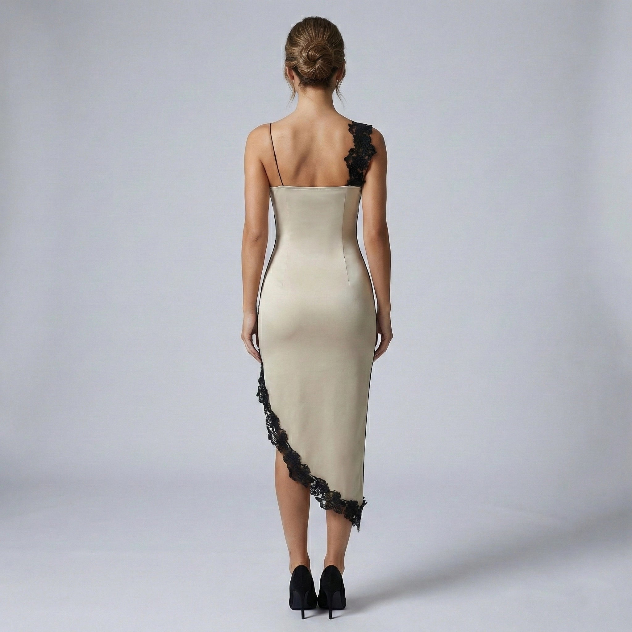 Woman wearing a beige evening gown with black lace details on a plain background