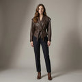 Woman wearing a brown leather jacket and black pants against a neutral background