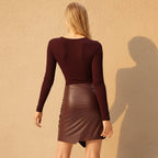 Woman wearing a maroon long-sleeve top and skirt on a white background