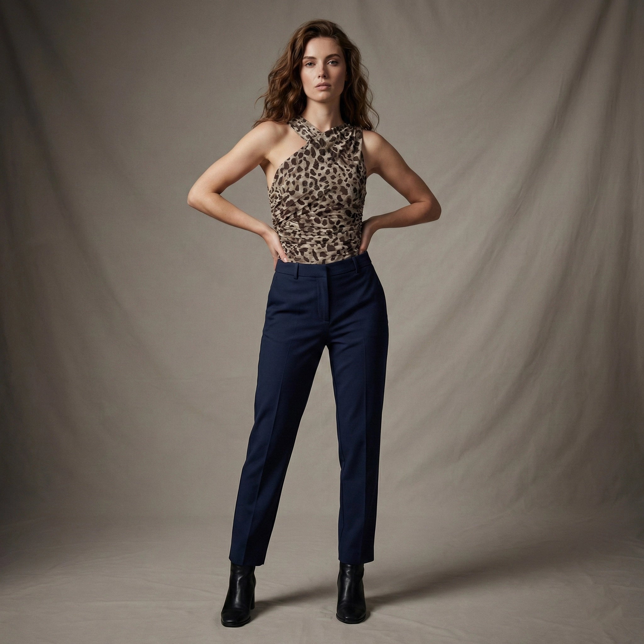 Woman wearing a leopard print top and navy pants against a plain background