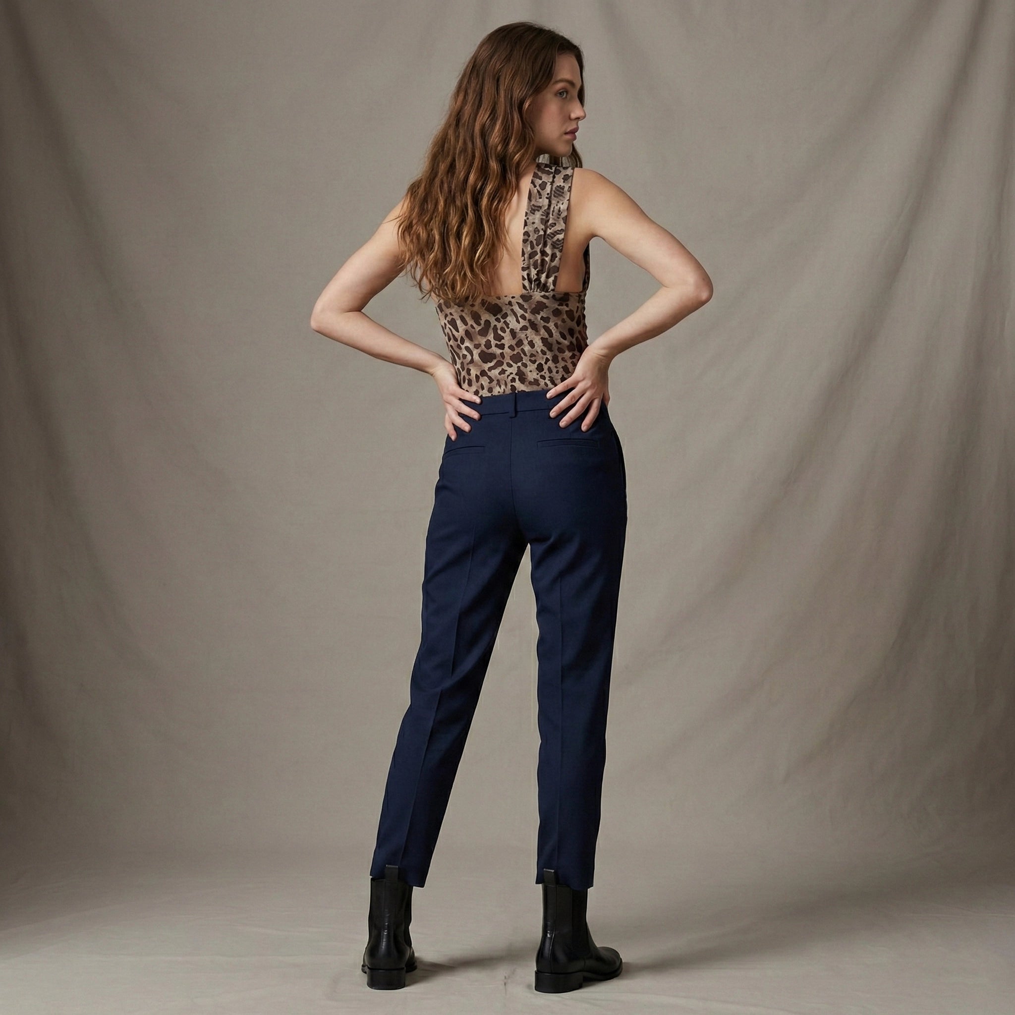 Woman wearing a leopard print top and navy pants against a plain background