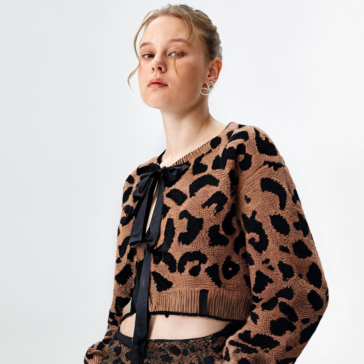 Woman wearing a leopard print sweater with a black ribbon on a white background