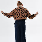 Person wearing a leopard print sweater and dark pants on a white background