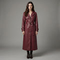 Woman wearing a long burgundy leather coat against a gray background