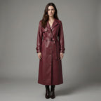 Woman wearing a long burgundy leather coat against a gray background
