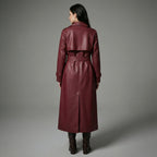 Woman wearing a burgundy leather trench coat against a gray background