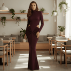 Woman in a burgundy dress standing in a modern cafe with plants and tables.
