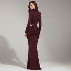 Woman wearing a burgundy evening gown with cut-out design on a neutral background