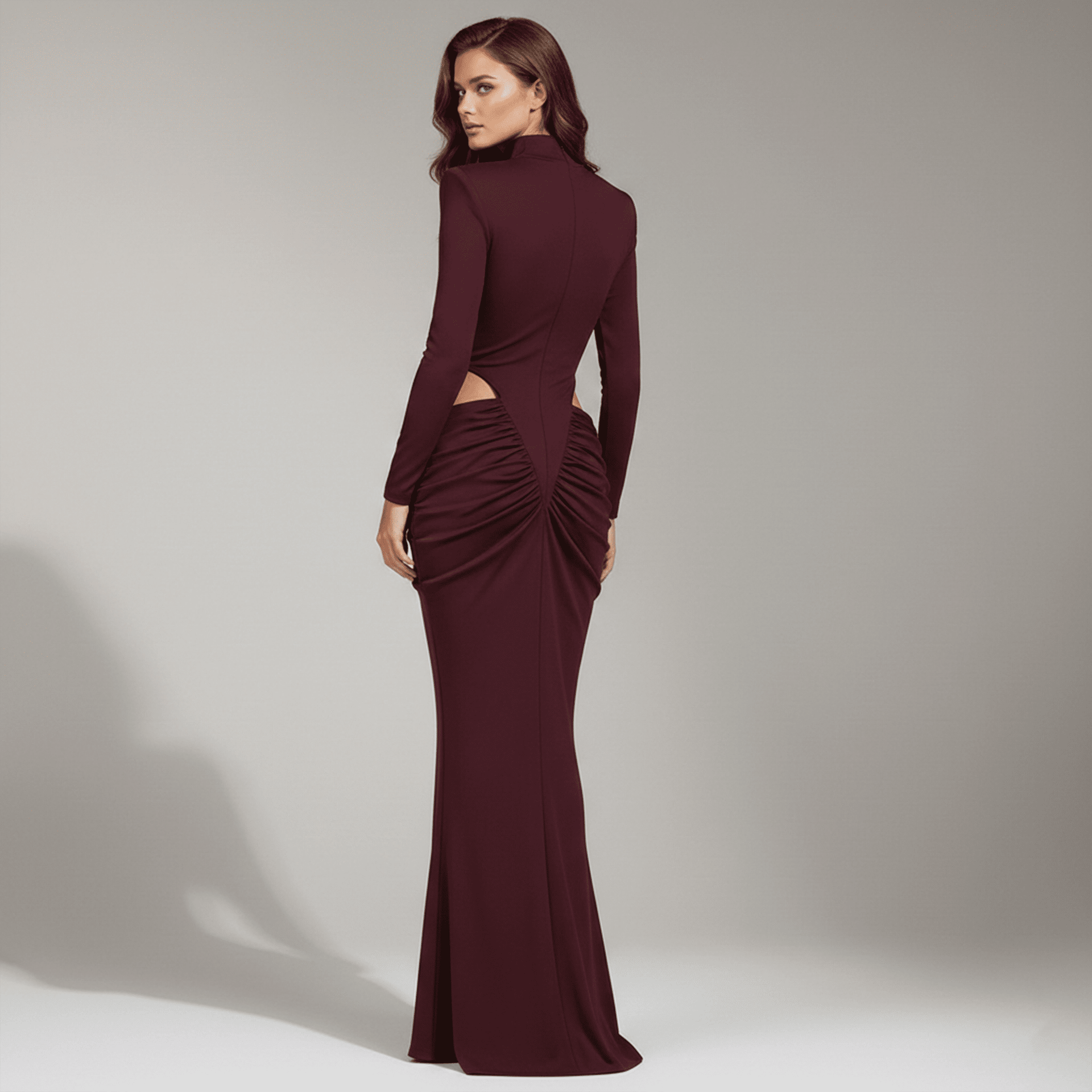 Woman wearing a burgundy evening gown with cut-out design on a neutral background