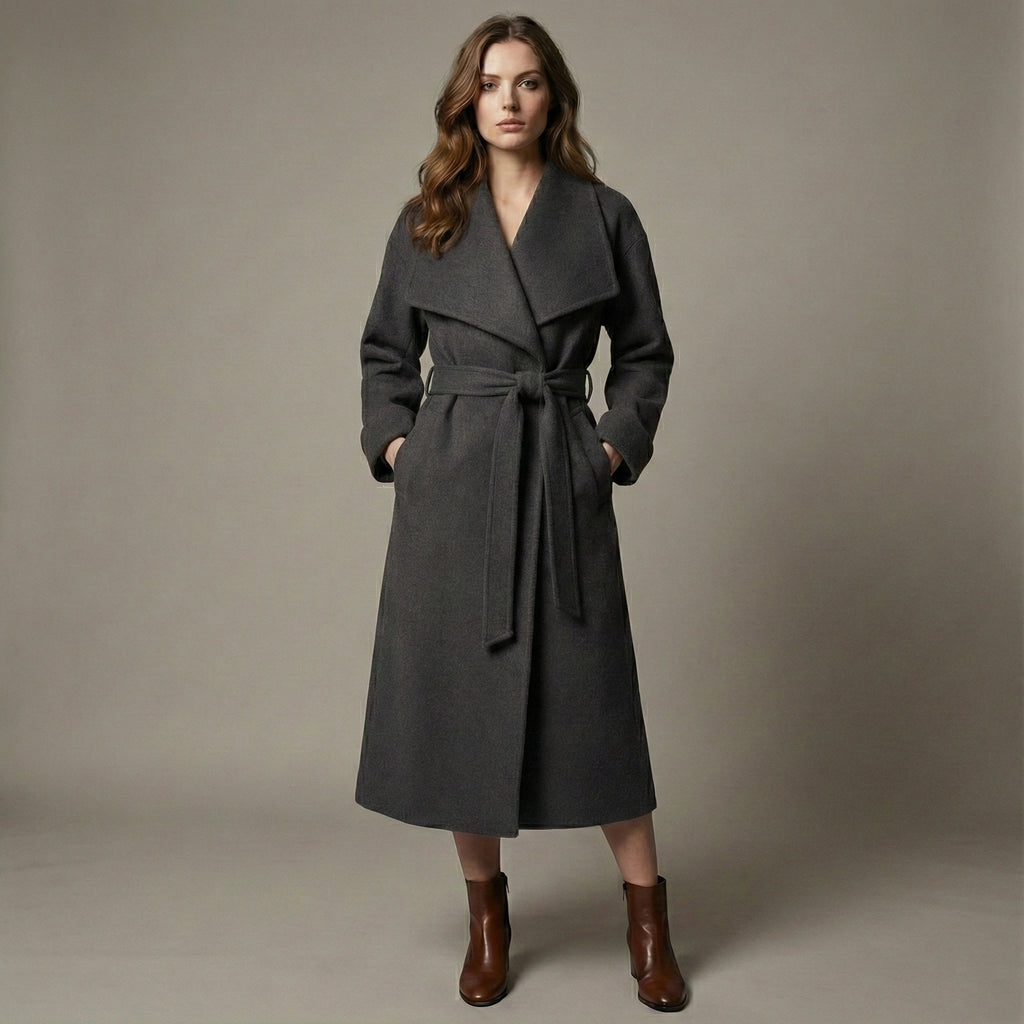 Woman wearing a gray coat with a belt against a plain background