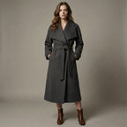 Woman wearing a gray coat with a belt against a plain background