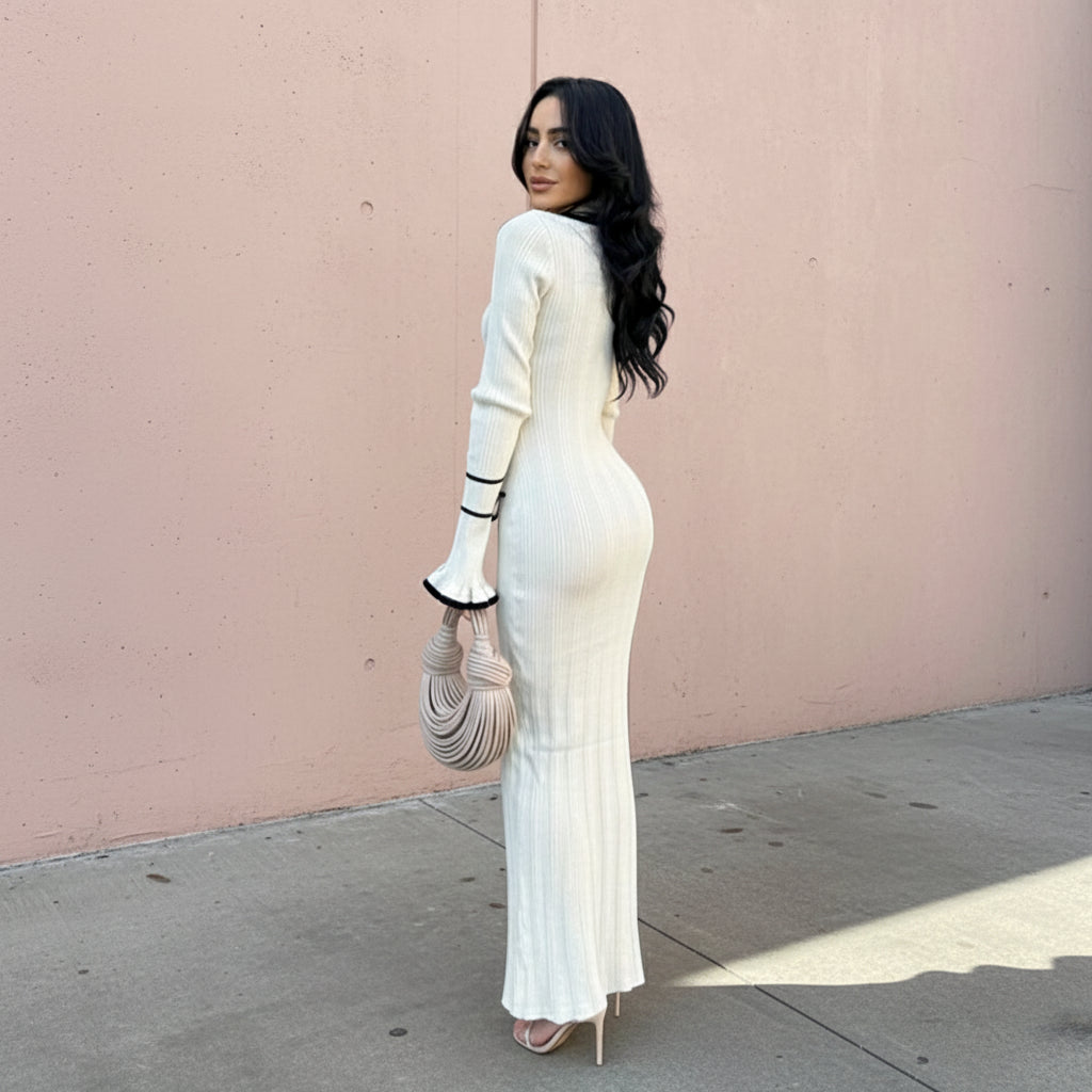 Woman wearing a white dress with black accents against a plain background