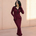 Woman wearing a burgundy dress with black trim on a gray background