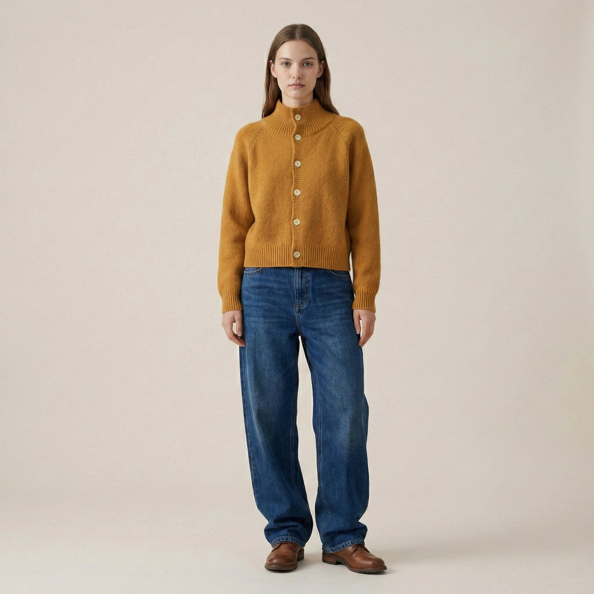 Woman wearing a mustard yellow sweater and blue jeans on a beige background