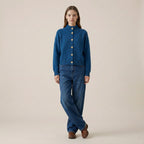 Woman wearing a blue jacket and jeans on a beige background