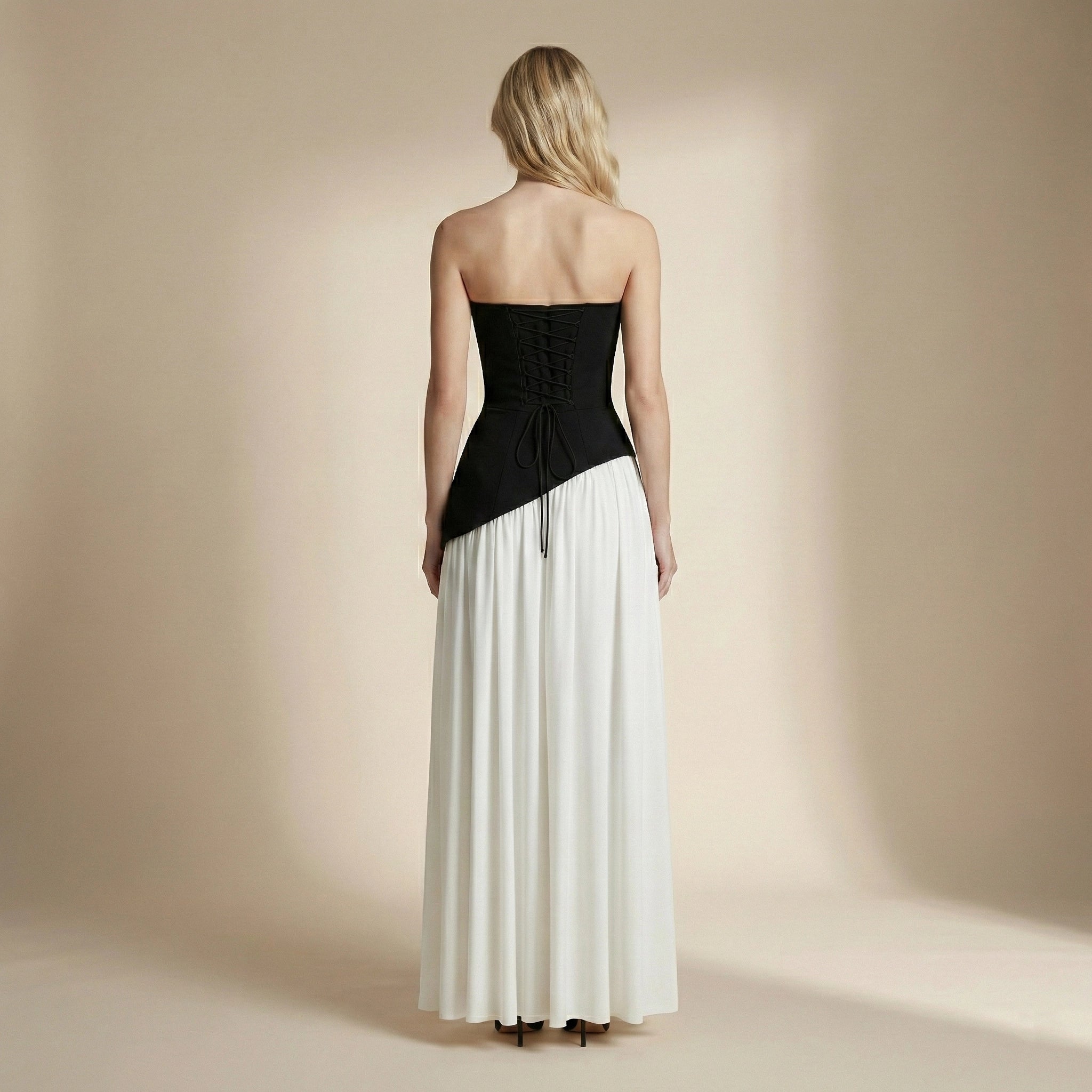 Woman wearing a black and white strapless dress against a beige background