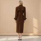 Woman wearing a brown trench coat against a beige wall