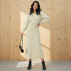 Woman wearing a beige coat holding a black handbag on a gray background