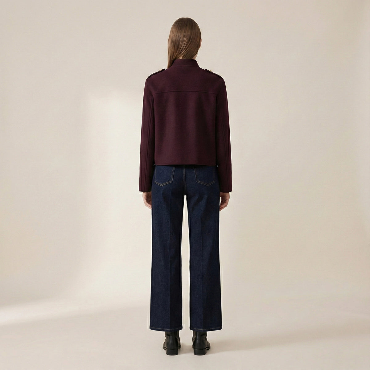 Person wearing a dark red shirt and blue jeans on a beige background
