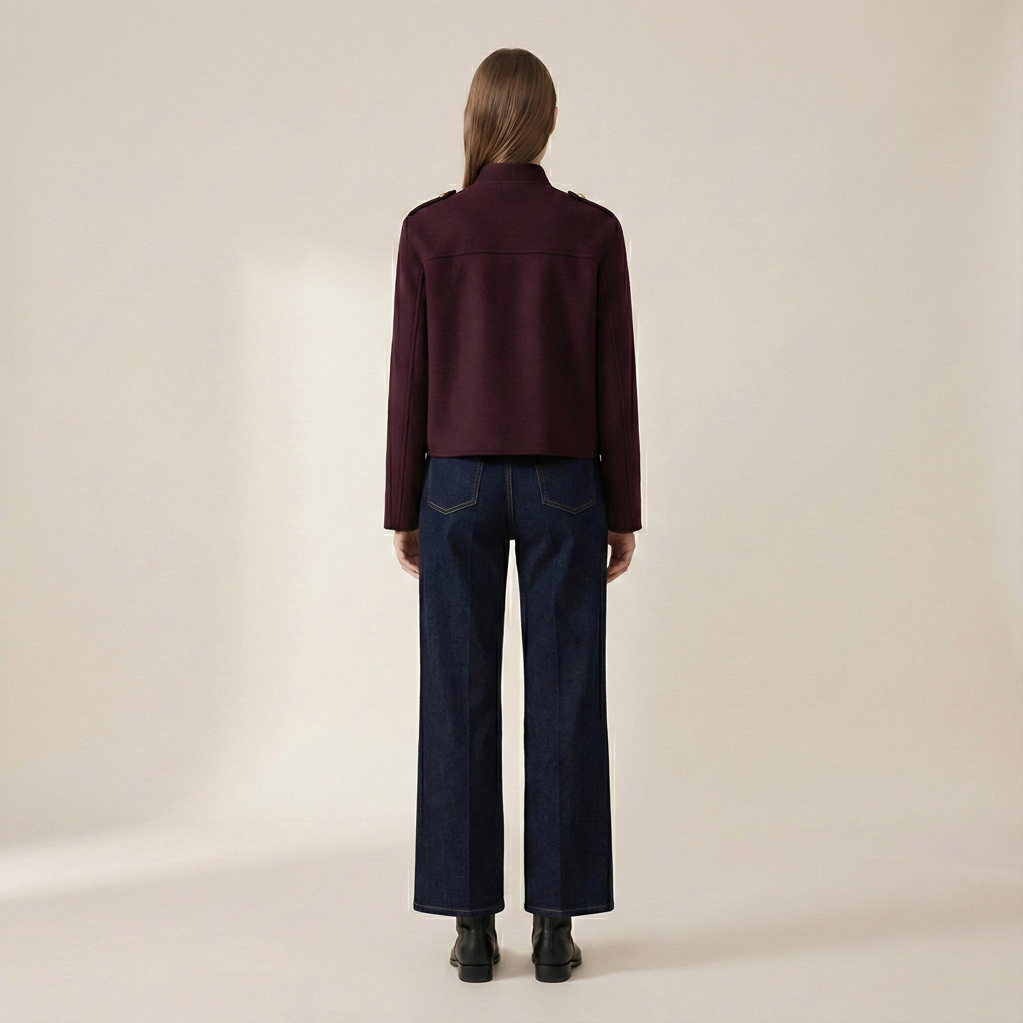 Person wearing a dark red shirt and blue jeans on a beige background