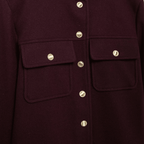 Close-up of a dark purple coat with gold buttons on a dark background