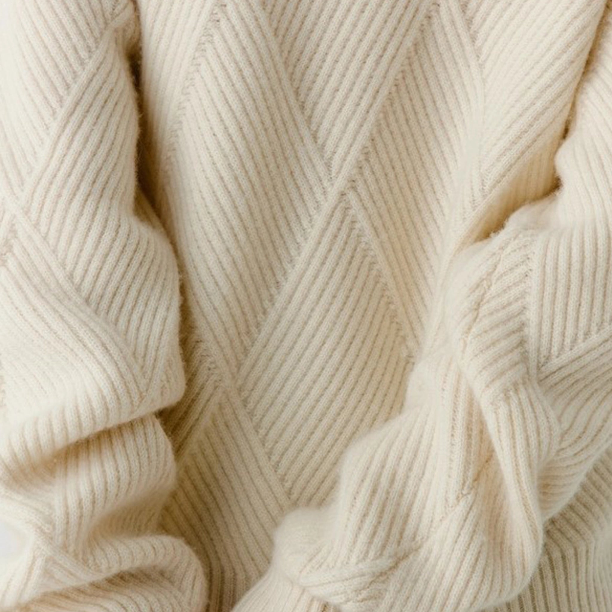 Close-up of a beige knitted fabric with a herringbone pattern