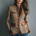 Woman wearing a brown jacket with leather accents against a gray background