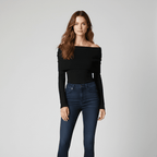 Woman wearing a black off-shoulder top and blue jeans on a gray background