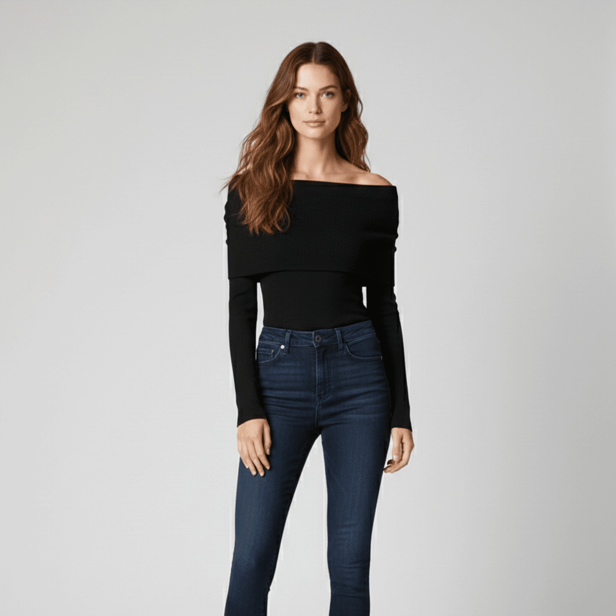 Woman wearing a black off-shoulder top and blue jeans on a gray background