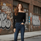 Woman in black top and blue jeans standing in front of a graffiti-covered brick wall.