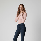 Woman wearing a pink off-shoulder top and dark blue jeans on a light gray background
