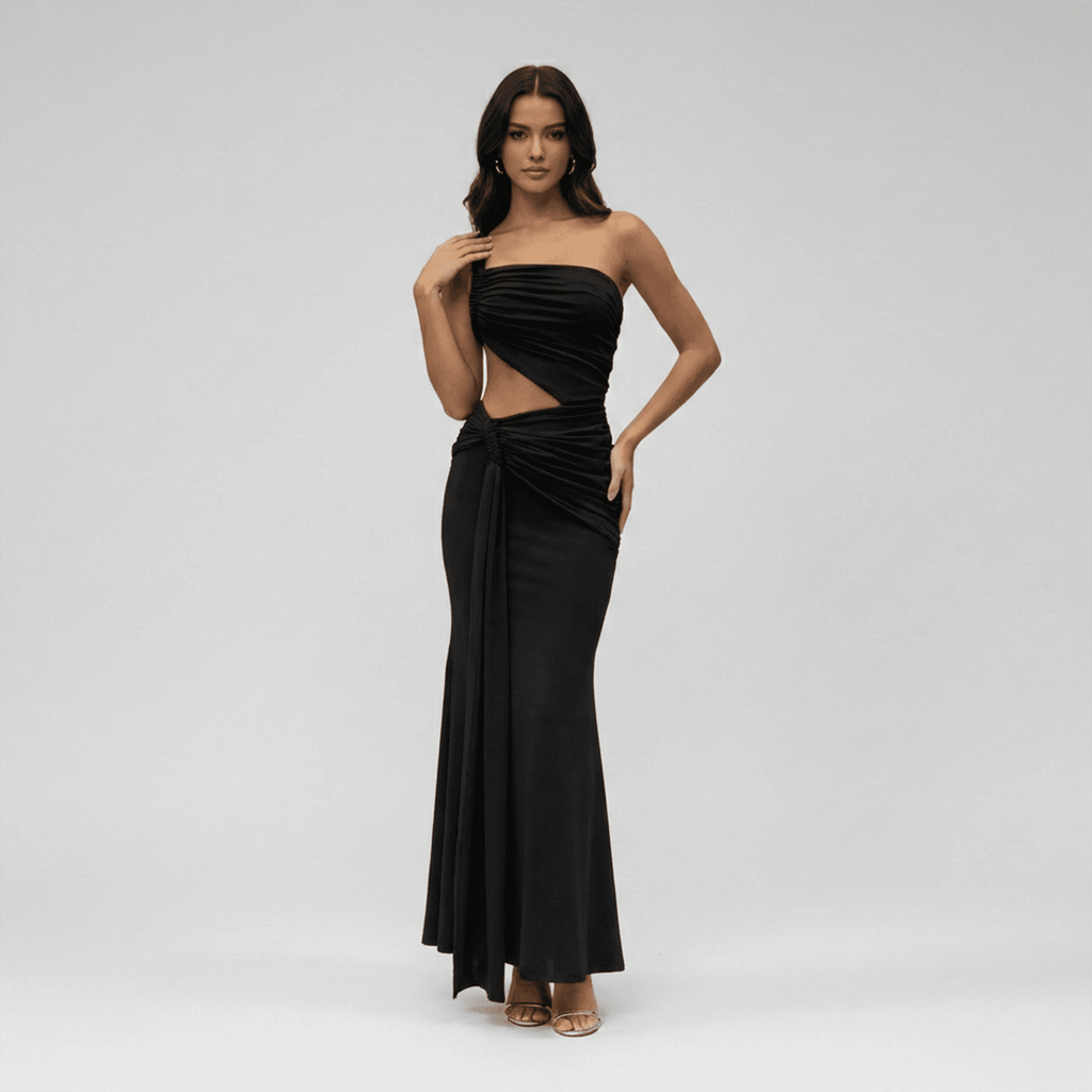 Woman wearing a black strapless gown with cut-out design on a gray background