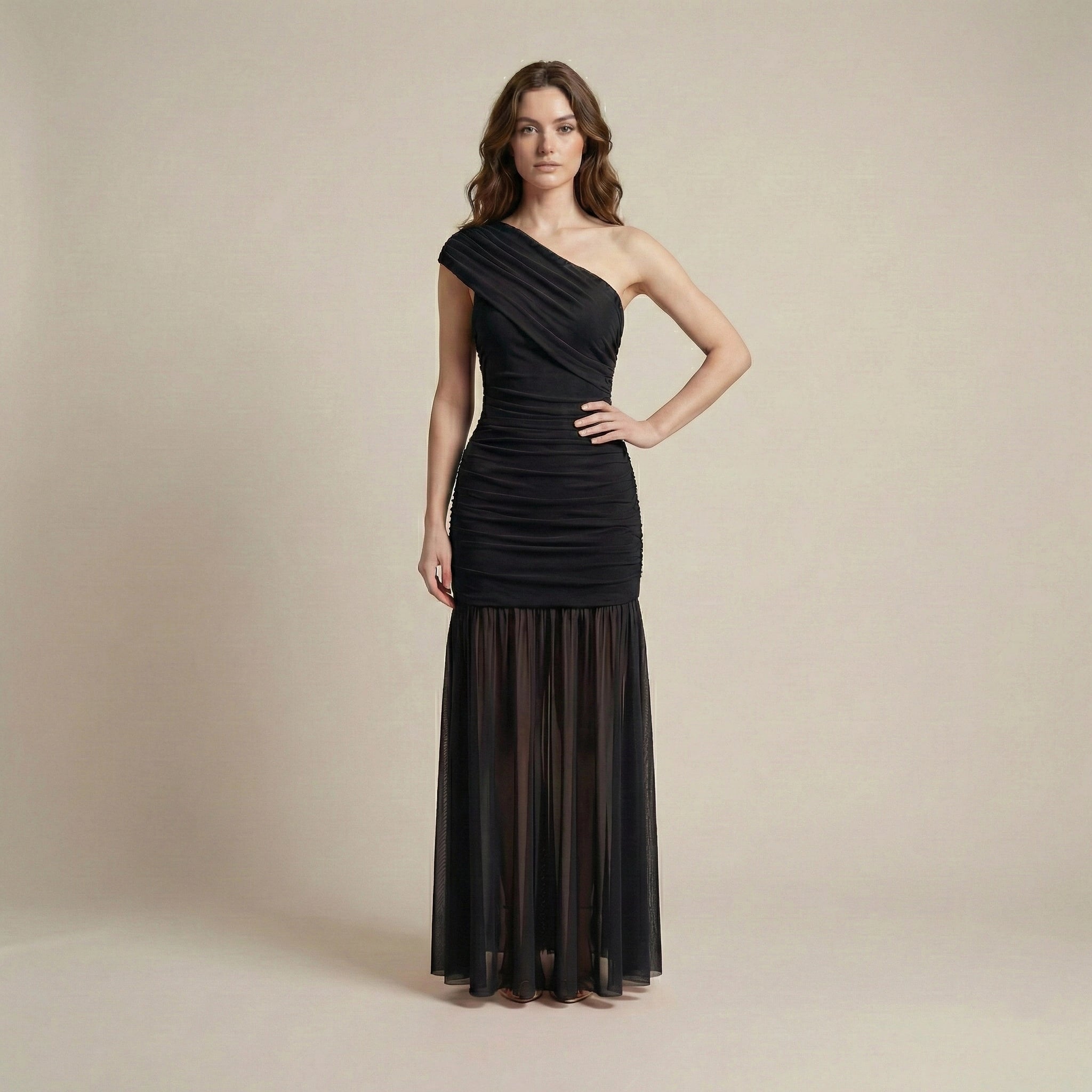 Woman wearing a black one-shoulder gown against a beige background