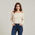 Woman wearing a cream off-shoulder sweater and blue jeans on a plain background