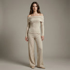 Woman wearing a beige off-shoulder top and pants against a plain background