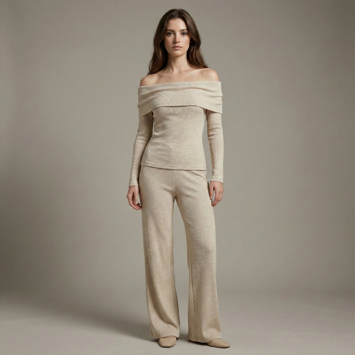 Woman wearing a beige off-shoulder top and pants against a plain background