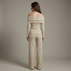 Woman wearing a beige off-shoulder top and pants against a plain background