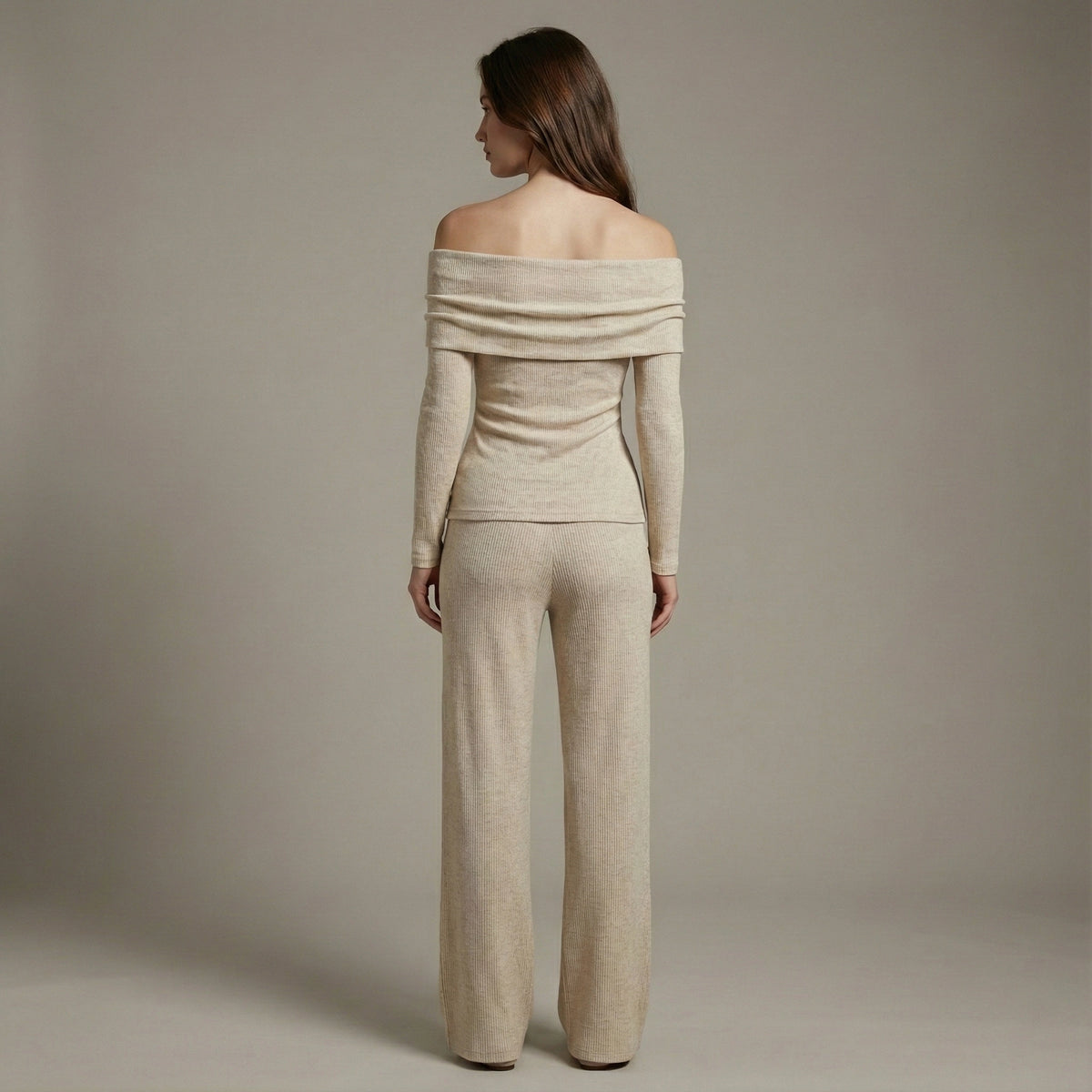 Woman wearing a beige off-shoulder top and pants against a plain background