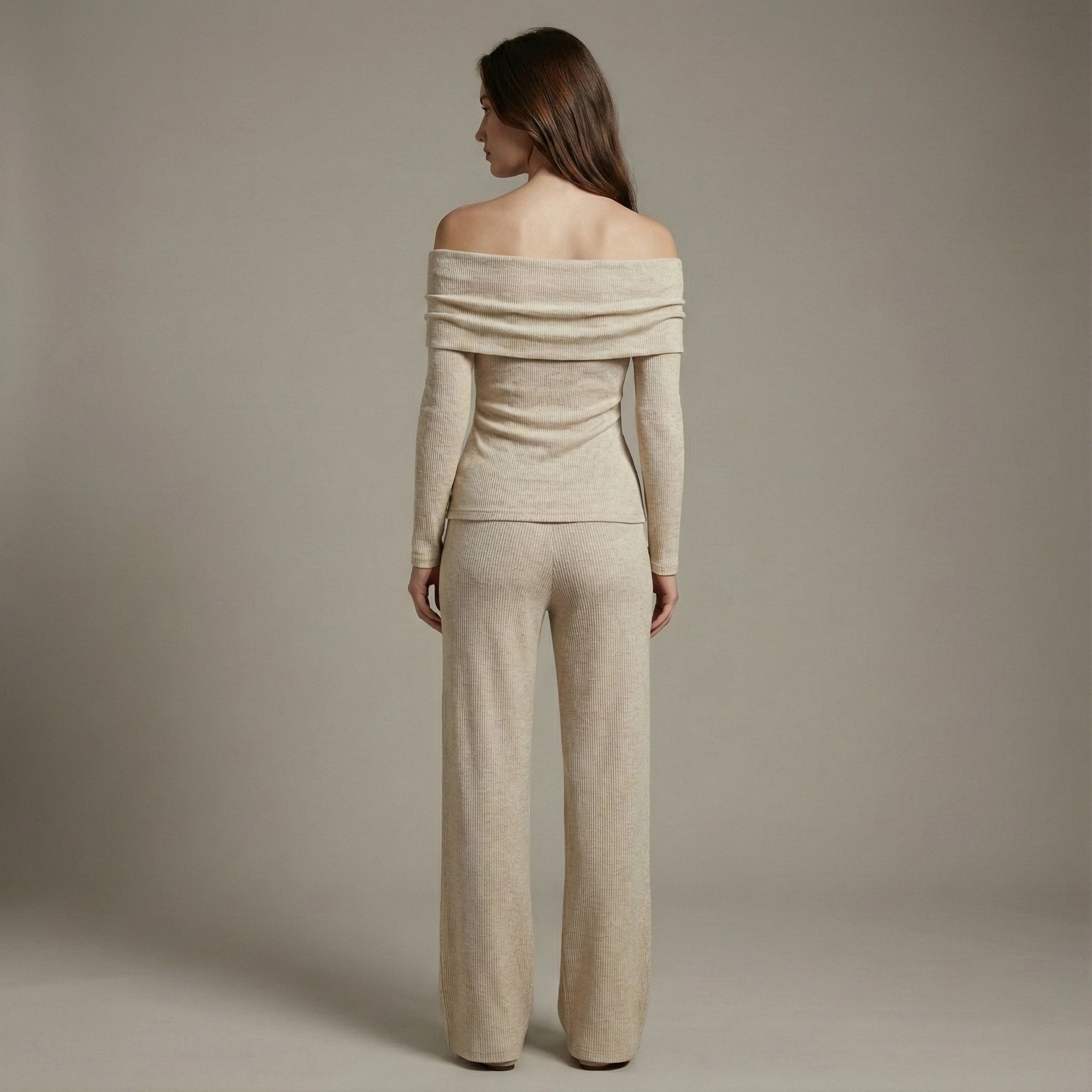 Woman wearing a beige off-shoulder top and pants against a plain background