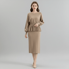 Woman wearing a beige peplum top and skirt on a gray background